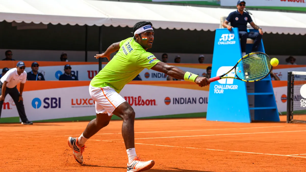 Indian tennis player on court, mid-forehand on a clay surface