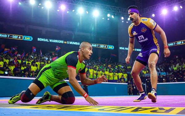 Two Pro Kabaddi players in a tense pre-raid face-off under bright arena lighting